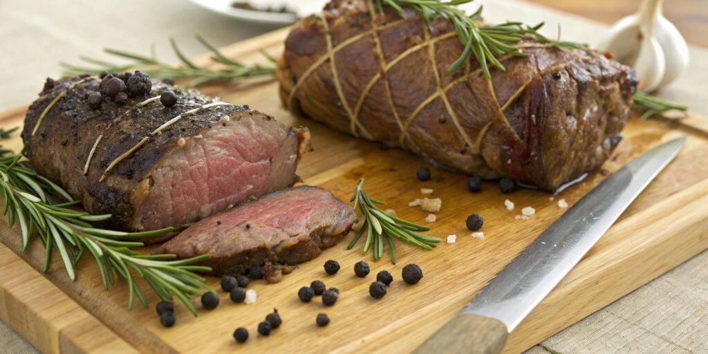 A side-by-side comparison of two venison roasts on a wooden cutting board, highlighting differences in texture and color