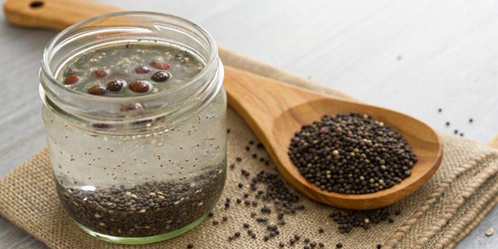A transparent jar filled with chia seeds soaking in water, showing their swollen, gelatinous texture as they absorb liquid.